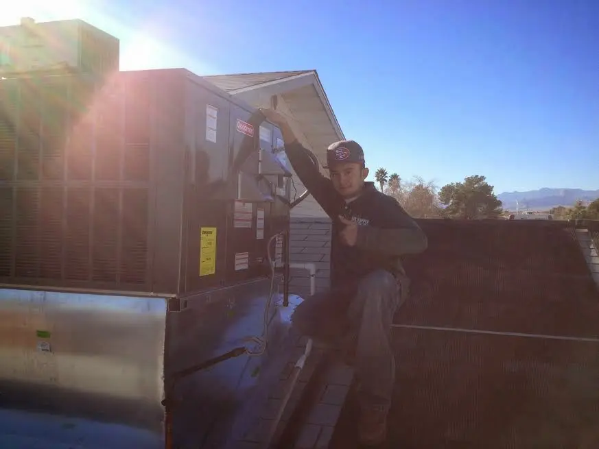 HVAC technician performing Heat Pump Repair on a rooftop unit in Holliston